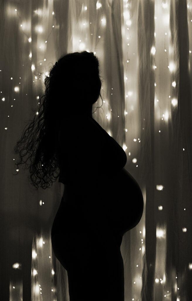 une silhouette de femme enceinte qui apparait grace a des guirlandes de lumiere.