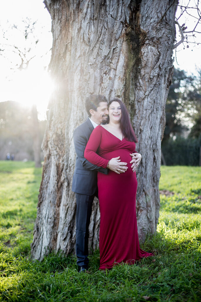 futurs parents ave la future maman en robe rouge pour mettre son ventre en avant.